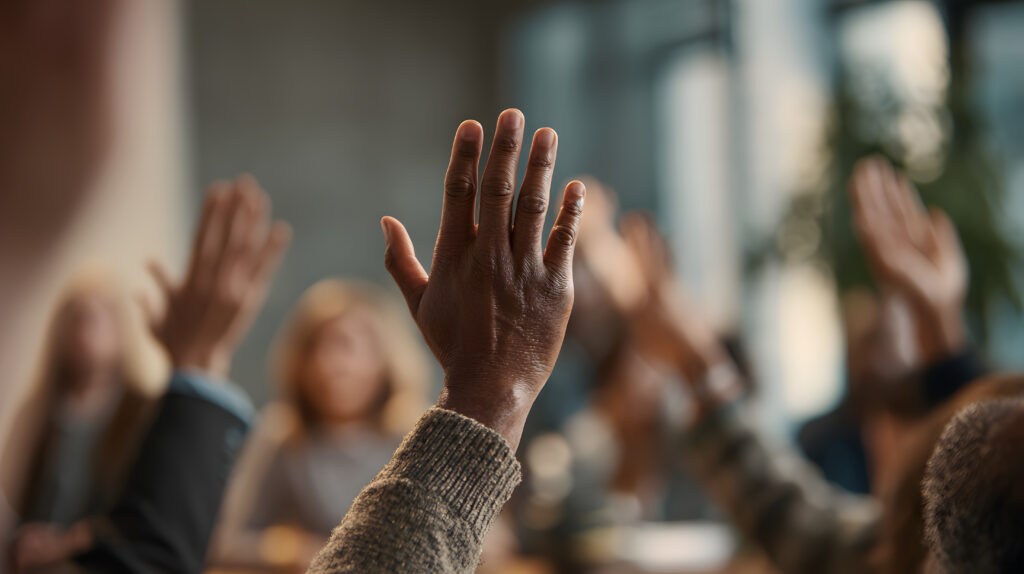 Hands raised in a meeting room, indicating participation and engagement from attendees during a discussion.
